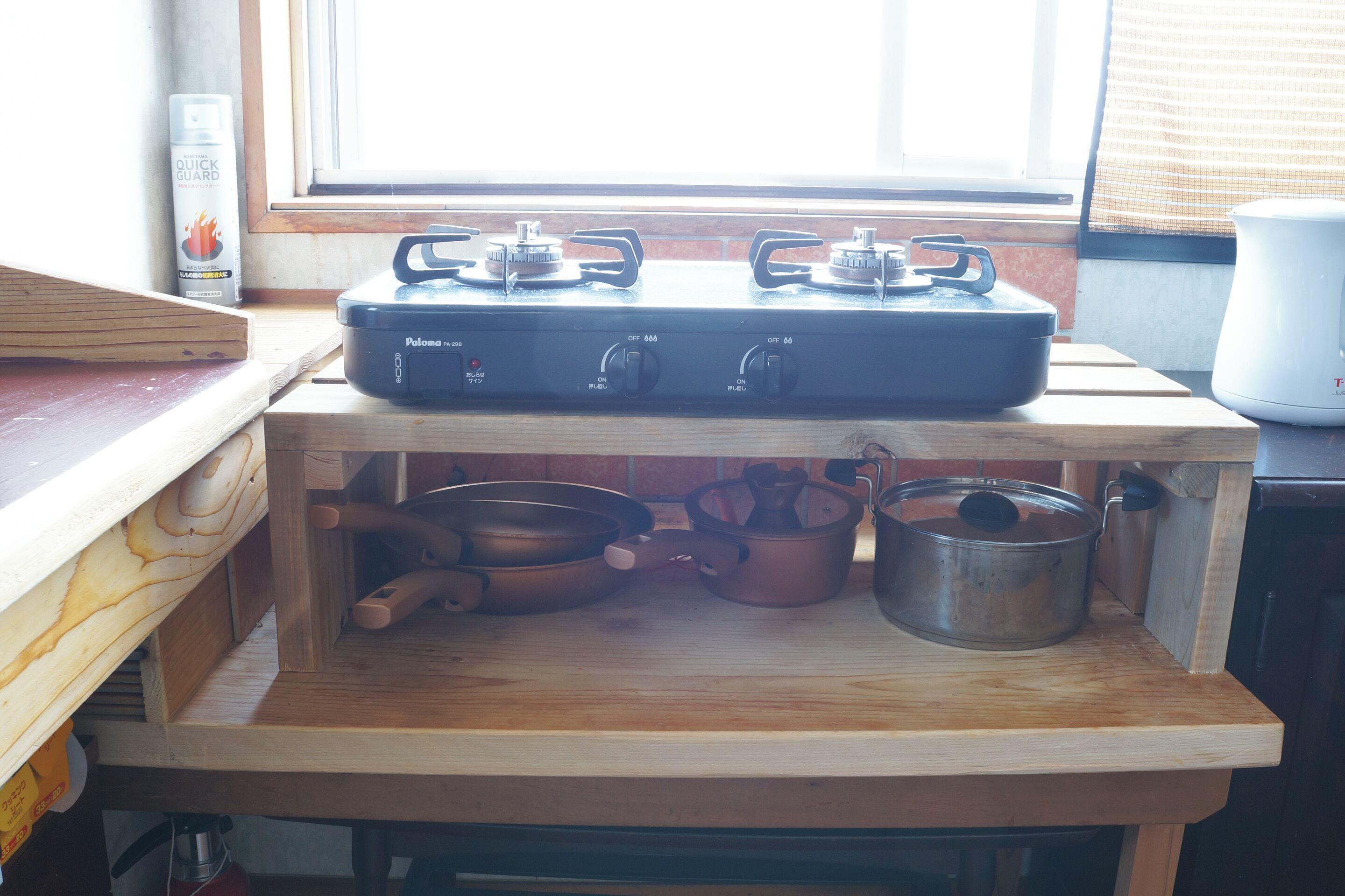 A kitchen with a gas stove, pots, and a window with blinds.