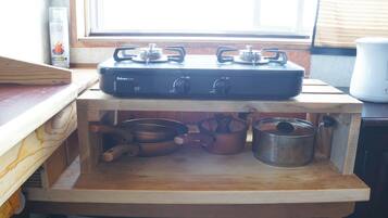 A kitchen with a gas stove, pots, and a window with blinds.