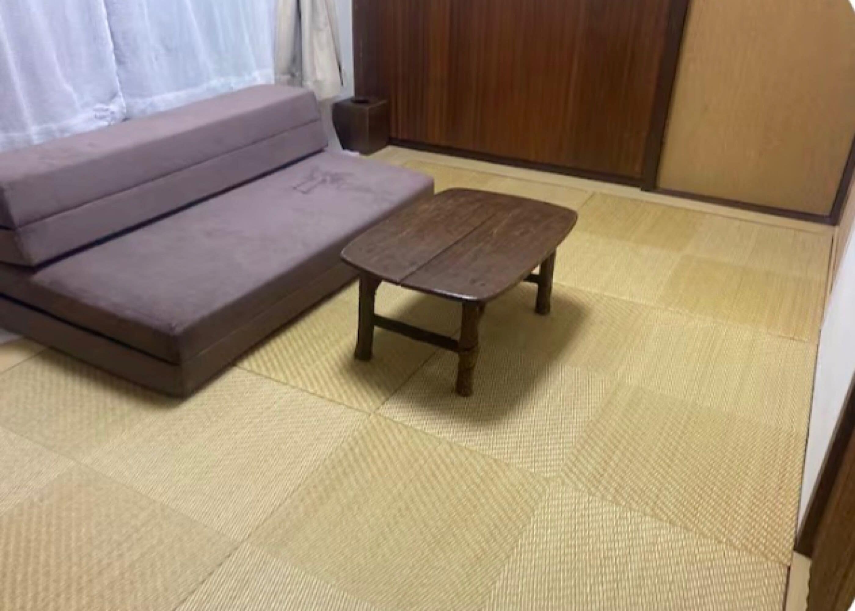 Una stanza con un divano e un piccolo tavolino in legno su pavimento in tatami.