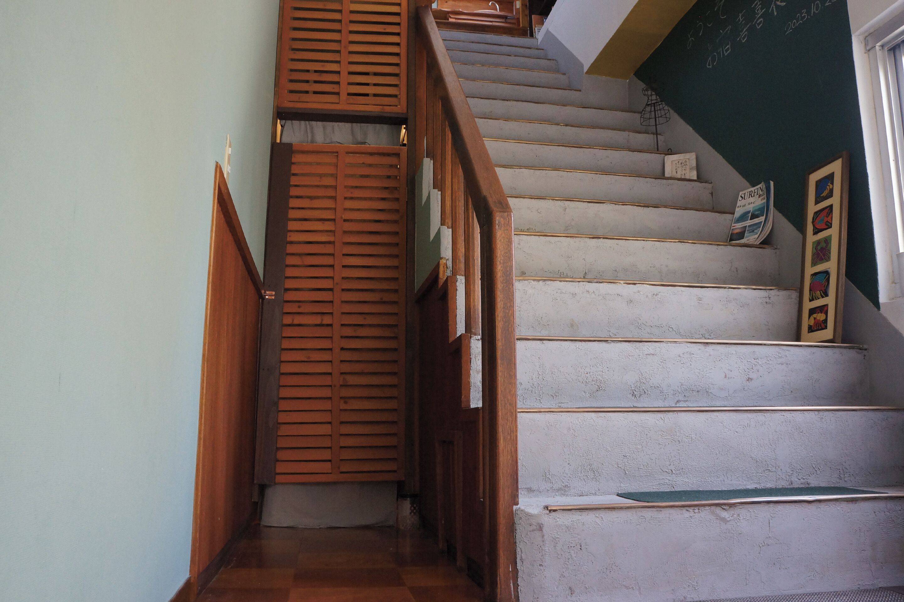 A staircase with wooden railings and a white wall with a calendar.