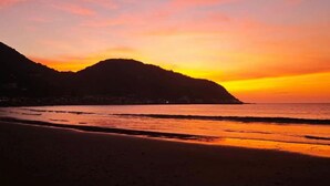 Tramonto su una spiaggia con una montagna sullo sfondo.