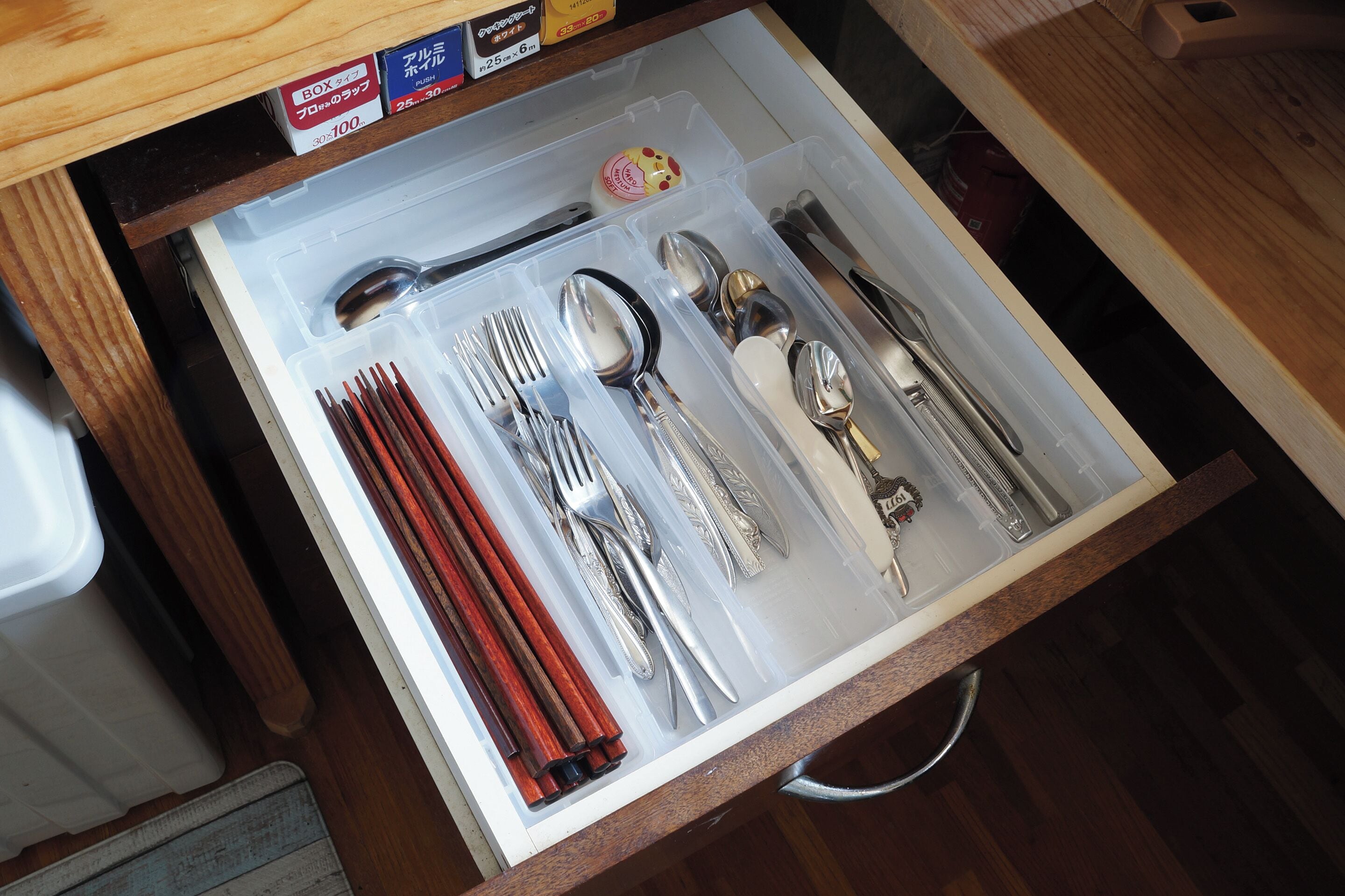 A drawer containing neatly organized cutlery and chopsticks.