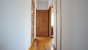 Un corridoio stretto con pavimento in legno e una porta in legno alla fine.