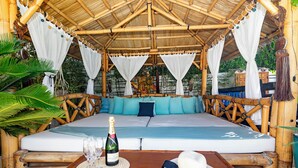 A bamboo-framed outdoor seating area with a mattress, pillows, and a bottle of champagne on a table. - Villa near Ibiza Town, sleeps 13 (Ibiza)