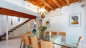 A dining area with a glass table, wooden chairs, a chandelier, and artwork on the walls. - Villa near Ibiza Town, sleeps 13 (Ibiza)