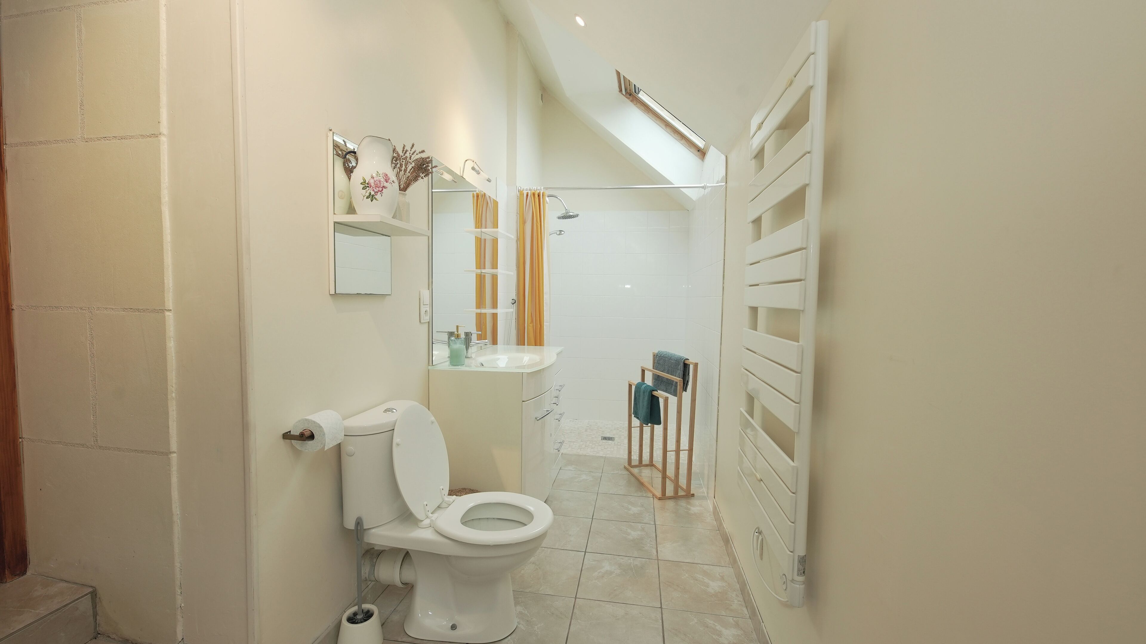 A narrow bathroom with a toilet, sink, and shower.