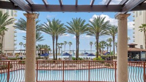 Zona de piscina con palmeras, una pérgola y vista al océano.