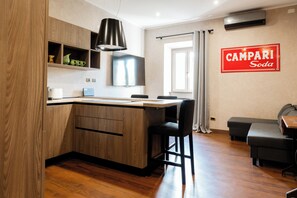 A modern kitchen with a wooden island, bar stools, and a flat-screen TV.