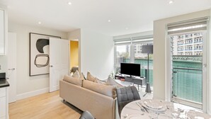 A modern living room with a sofa, dining table set, and a TV.