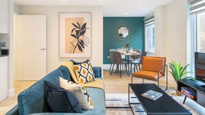 A modern living room with a sofa, coffee table, and a dining area with chairs and a table.