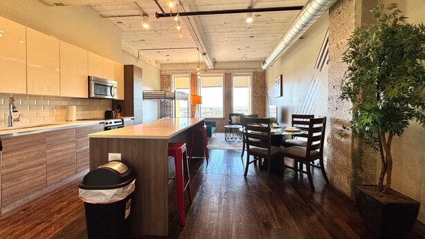 A modern kitchen with a central island, wooden cabinets, and a stainless steel microwave.