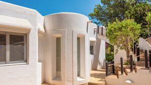 Un edificio blanco con una esquina curva, una ventana y una escalera con barrera de cuerda.