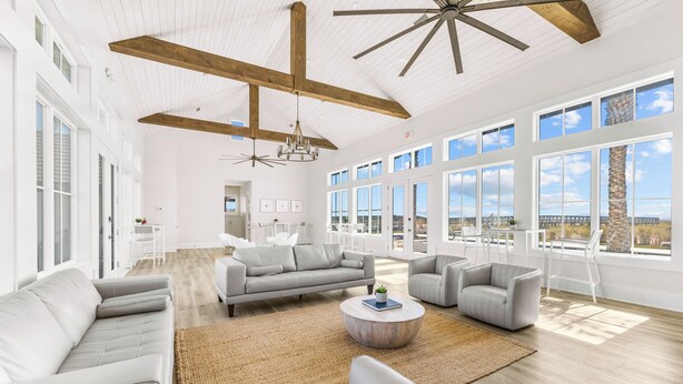 A spacious living area with a large sofa set, a coffee table, and a view of the outdoors through large windows.