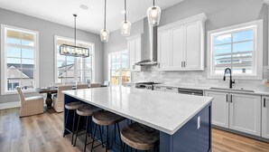 A modern kitchen with a large island, bar stools, and a view of the outside.