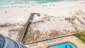A beach view with a pool area, a wooden deck, and beach umbrellas. - Phoenix IX 903 - Beautiful 2BR Gulf Front Unit (Orange Beach)