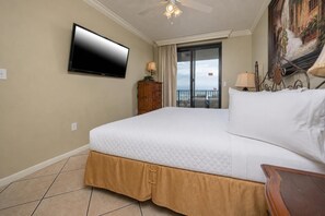 Habitación de hotel con cama, televisión montada en la pared, balcón con vistas y un cuadro en la pared.