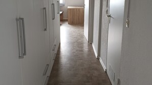 A hallway with white walls and wooden flooring leading to a room with a bed and a window. - Beautiful apartment 27b near Mainz University Hospital (Mainz)