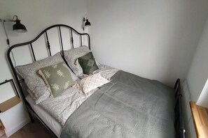 Een bed met hoofdeinde, twee wandlampen en een nachtkastje met een lamp.