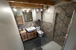 A bathroom with a shower, toilet, sink, and wooden cabinets.