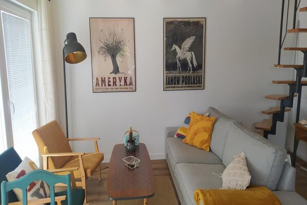 A living room with a sofa, armchair, coffee table, and a staircase.