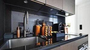 A modern kitchen with a black countertop, stainless steel sink, and wooden cabinets. - AN IDEAL BASE FOR YOUR PARISIAN ADVENTURE, LOCATED AT RUE JACOB - SAINT GERMAIN (Paris)