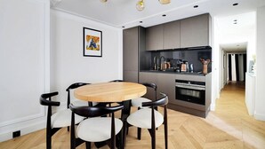 A modern kitchen with dark cabinets, a built-in oven, and a black countertop. - AN IDEAL BASE FOR YOUR PARISIAN ADVENTURE, LOCATED AT RUE JACOB - SAINT GERMAIN (Paris)