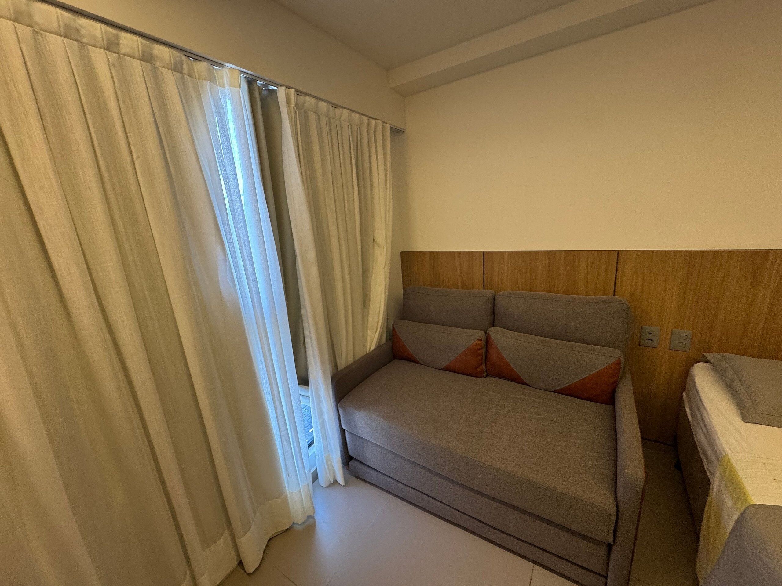 A room with a sofa, a bed, and a curtain.