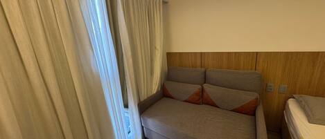 A room with a sofa, a bed, and a curtain.