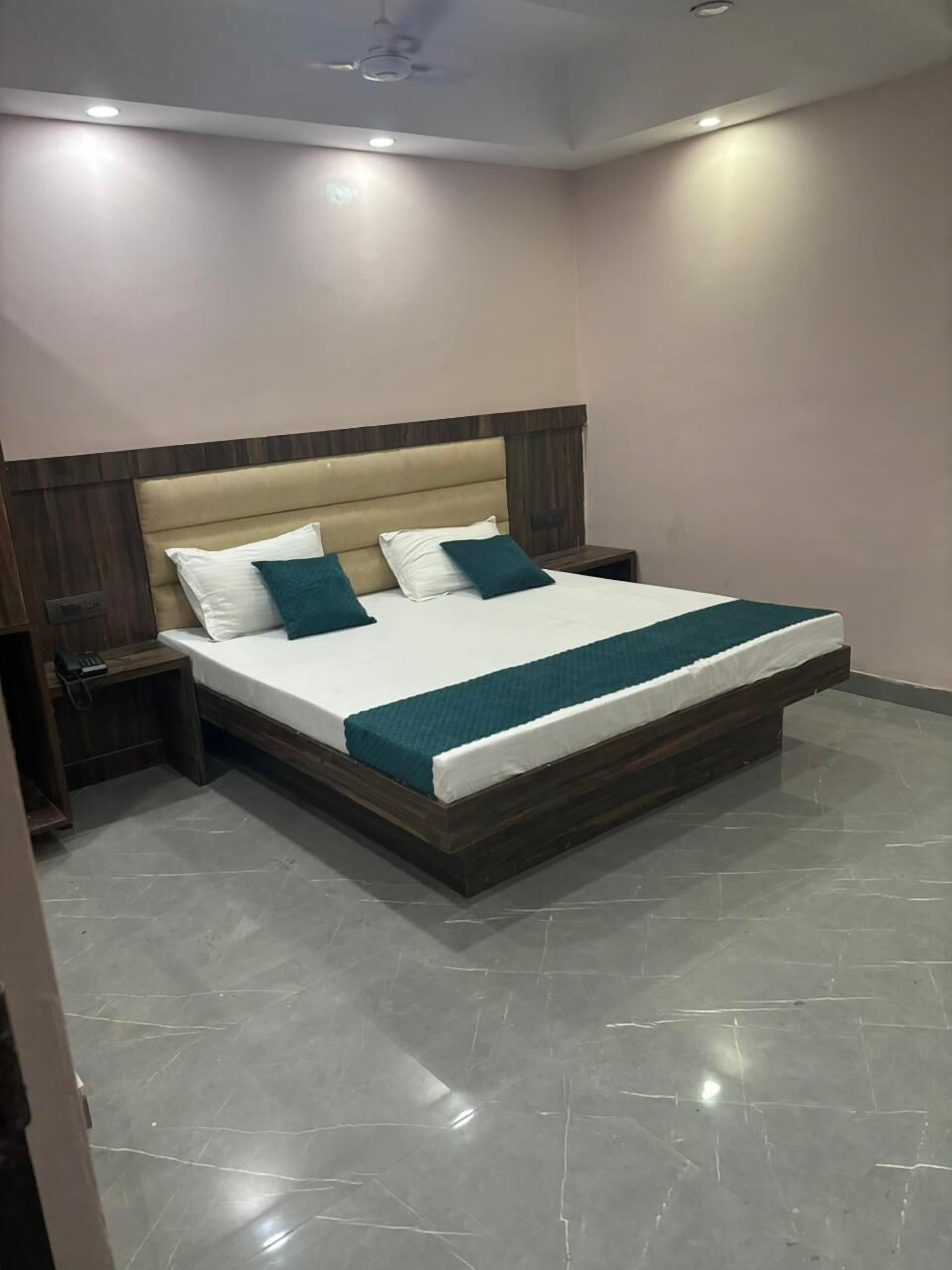 A modern bedroom with a large bed, wooden headboard, and a nightstand.