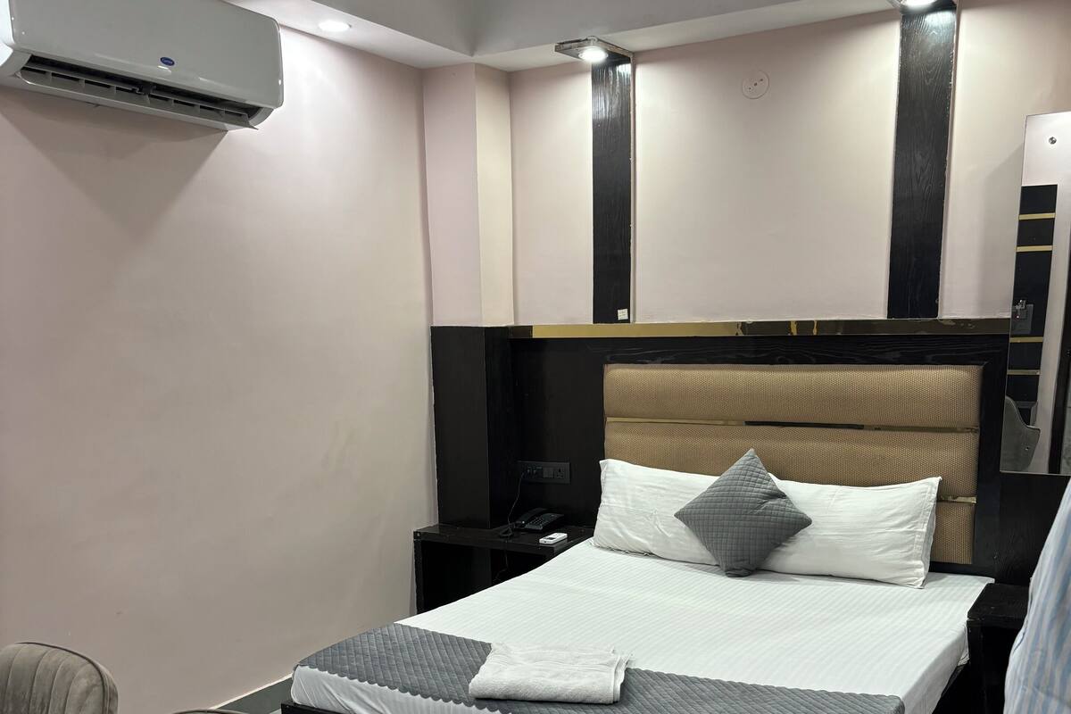 A modern hotel room with a large bed, a bedside table, a chair, and a desk.