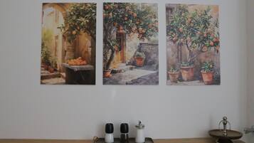 A wall with three paintings of orange trees and a wooden table with salt and pepper shakers.