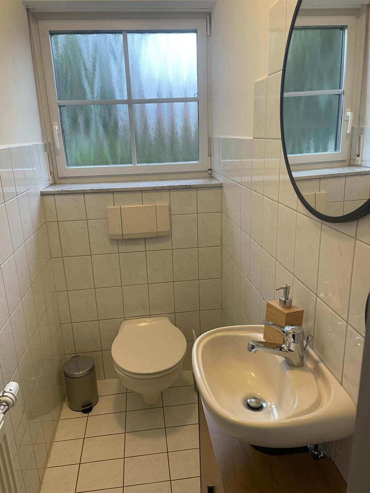 A small bathroom with a toilet, sink, and window.