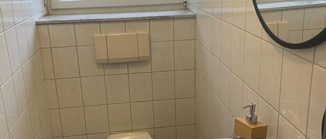 A small bathroom with a toilet, sink, and window.