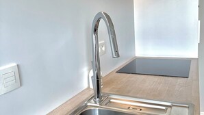 Una cucina moderna con lavello in acciaio inossidabile, un rubinetto elegante e una cappa aspirante integrata.