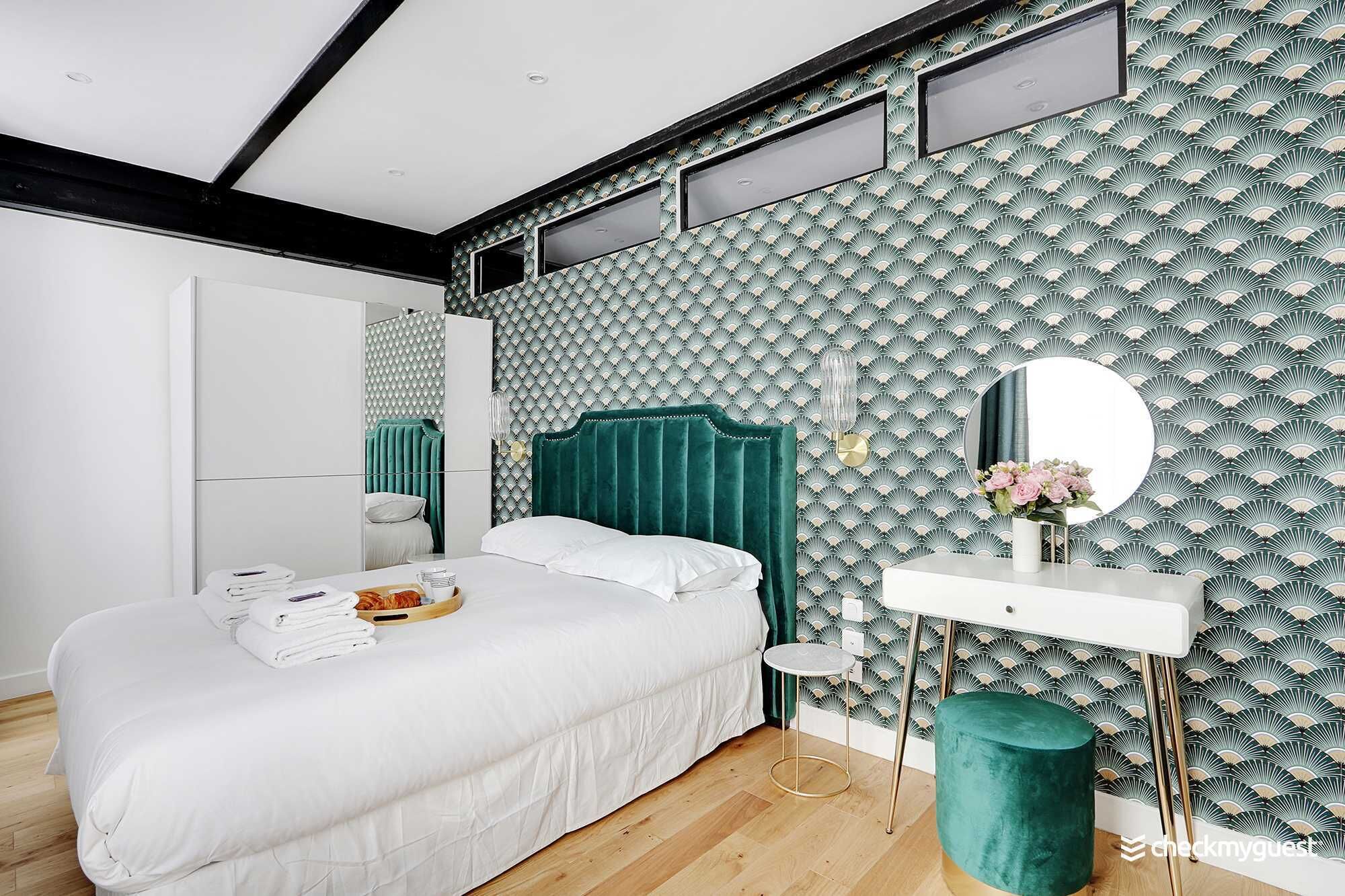 Une chambre moderne comprenant un lit, une table de chevet, un miroir et un motif décoratif sur le mur.