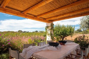 Un espace extérieur abrité, aménagé pour les repas, avec une table pour deux, donnant sur un vignoble.