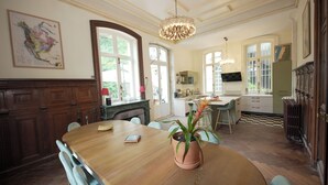 A dining area with a wooden table, chairs, a potted plant, and a chandelier. - The Château and its Orangery (Langeais)