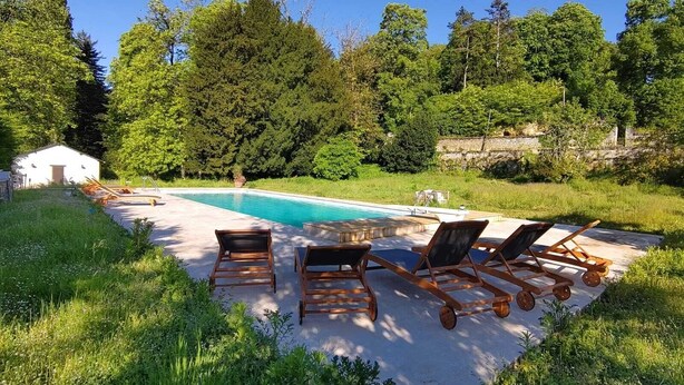 A swimming pool with lounge chairs and a small shed in a lush, green setting. - The Château and its Orangery (Langeais)