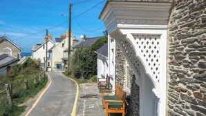 A narrow street with stone houses, a bench, and a white lattice structure. - Bywell, Llangrannog - Three Bedroom Cottage, Sleeps 6 (Llangrannog)