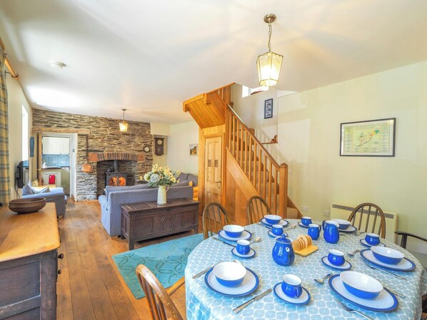 A dining area with a round table set for six, a fireplace, and a staircase leading to another level.