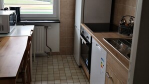 A compact kitchen with a window, a microwave, a refrigerator, an oven, and a dishwasher.