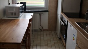 A compact kitchen with a window, a microwave, a refrigerator, and a sink.
