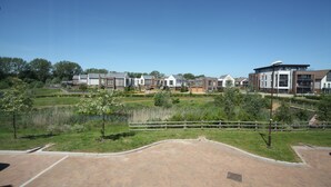 A residential area with modern houses, a paved walkway, and a small pond. - Luxurious 4 BH Home Near Willen Lake Ideal for Families & Business Stays! (Milton Keynes)