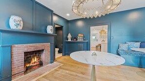 Une pièce avec une cheminée en briques, une table ronde en marbre et un mur d’accent bleu.