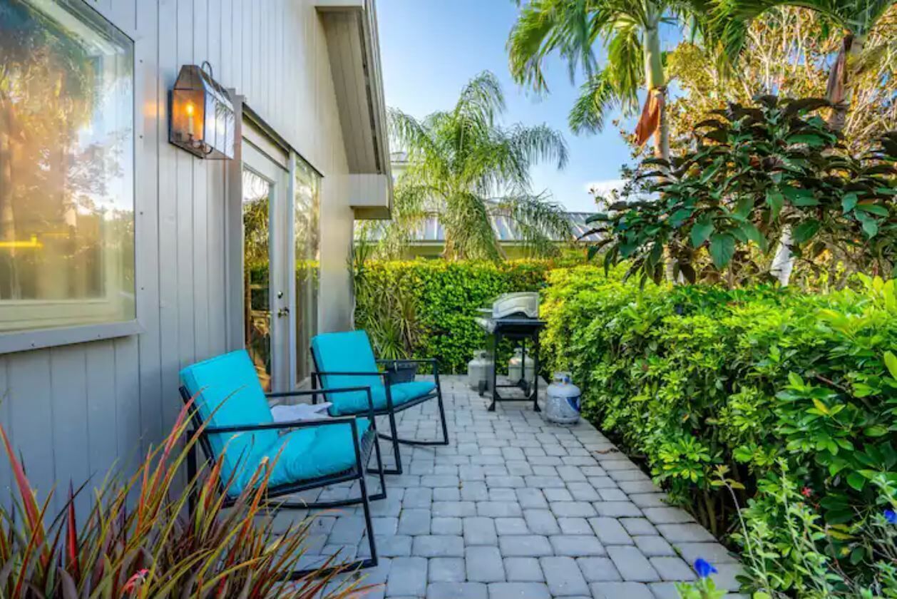 A patio with two blue chairs, a table, and a lantern.