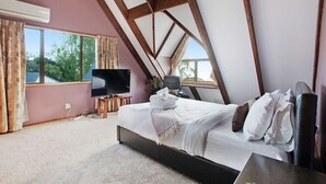 A bedroom with a large bed, a TV, and a window with curtains.