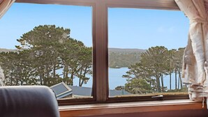 A room with a large window overlooking a lake and trees.
