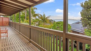 A wooden deck with a view of a coastal landscape, including palm trees and a body of water.