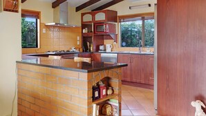 A kitchen with a central island, wooden cabinets, a microwave, and a window providing natural light.