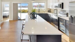 Una cocina moderna con una isla grande, electrodomésticos de acero inoxidable y vistas al exterior.